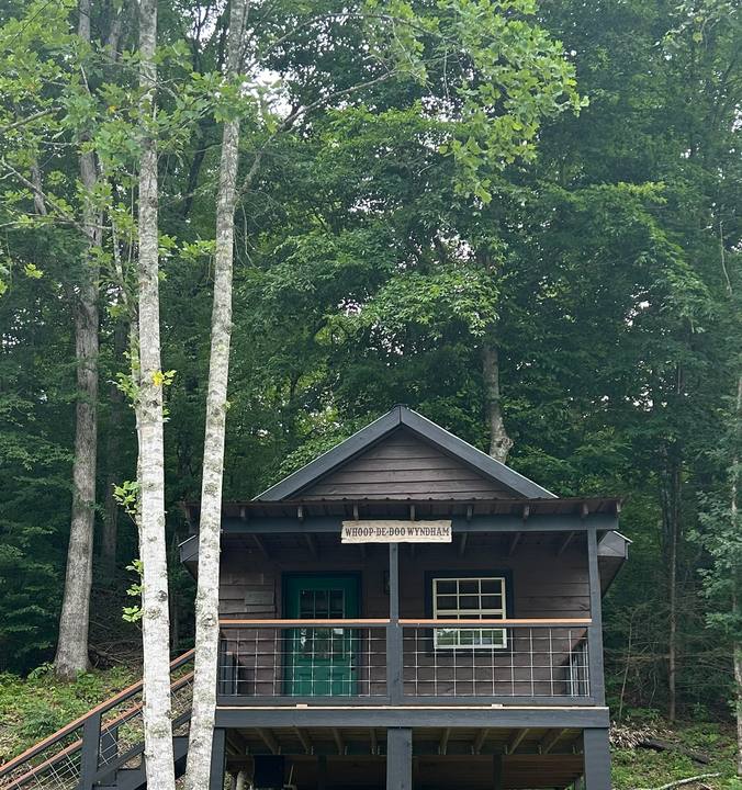 A wooden cabin with a railed porch among tall trees