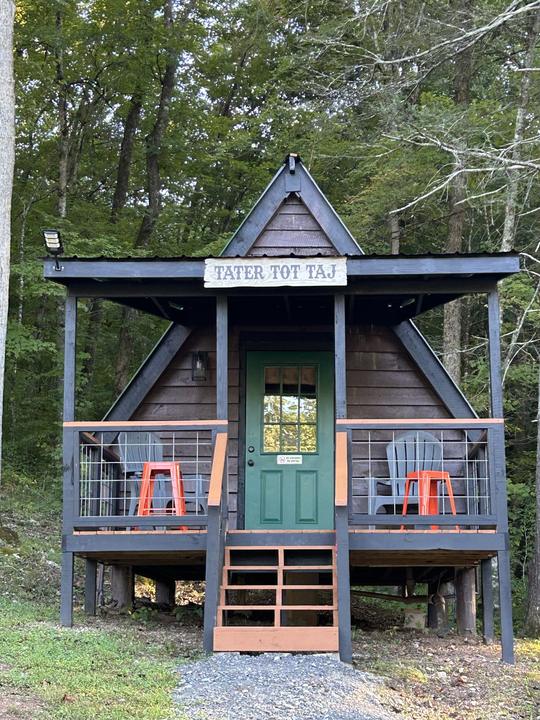 The Tater Tot Taj, an A-frame cabin with a green door and orange stools on the porch