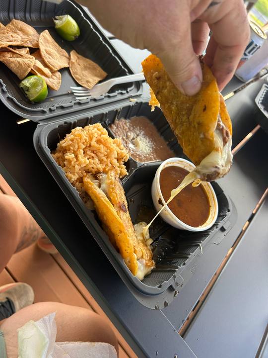 A takeout tray of fried food with dipping sauce