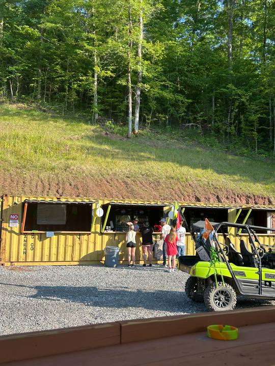 Guests at the service window of a container building set into the hillside, a side-by-side parked out front